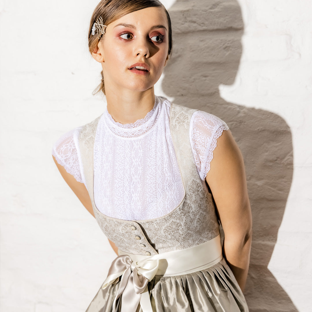 Hochzeitsdirndl mit creme-weiĂen Brokatmuster mit SeidenschĂŒrze und Dirndlbluse.