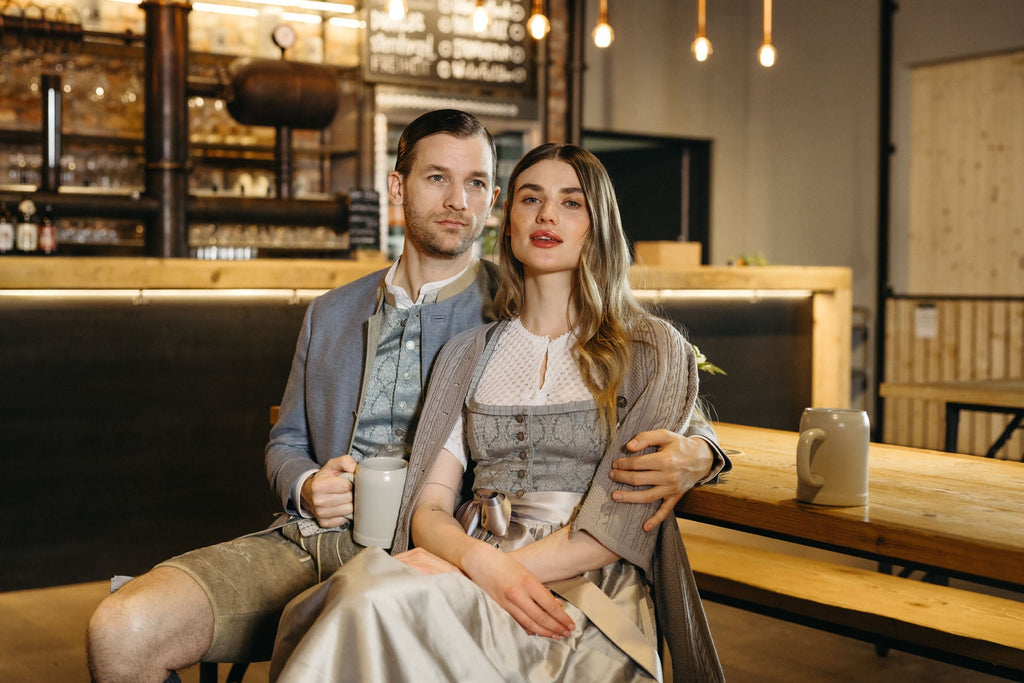 Braut im dunkelblauen Hochzeitsdirndl mit Blumenstrauß und Bräutigam im Trachtenjanker – eleganter Look für eine moderne Trachtenhochzeit