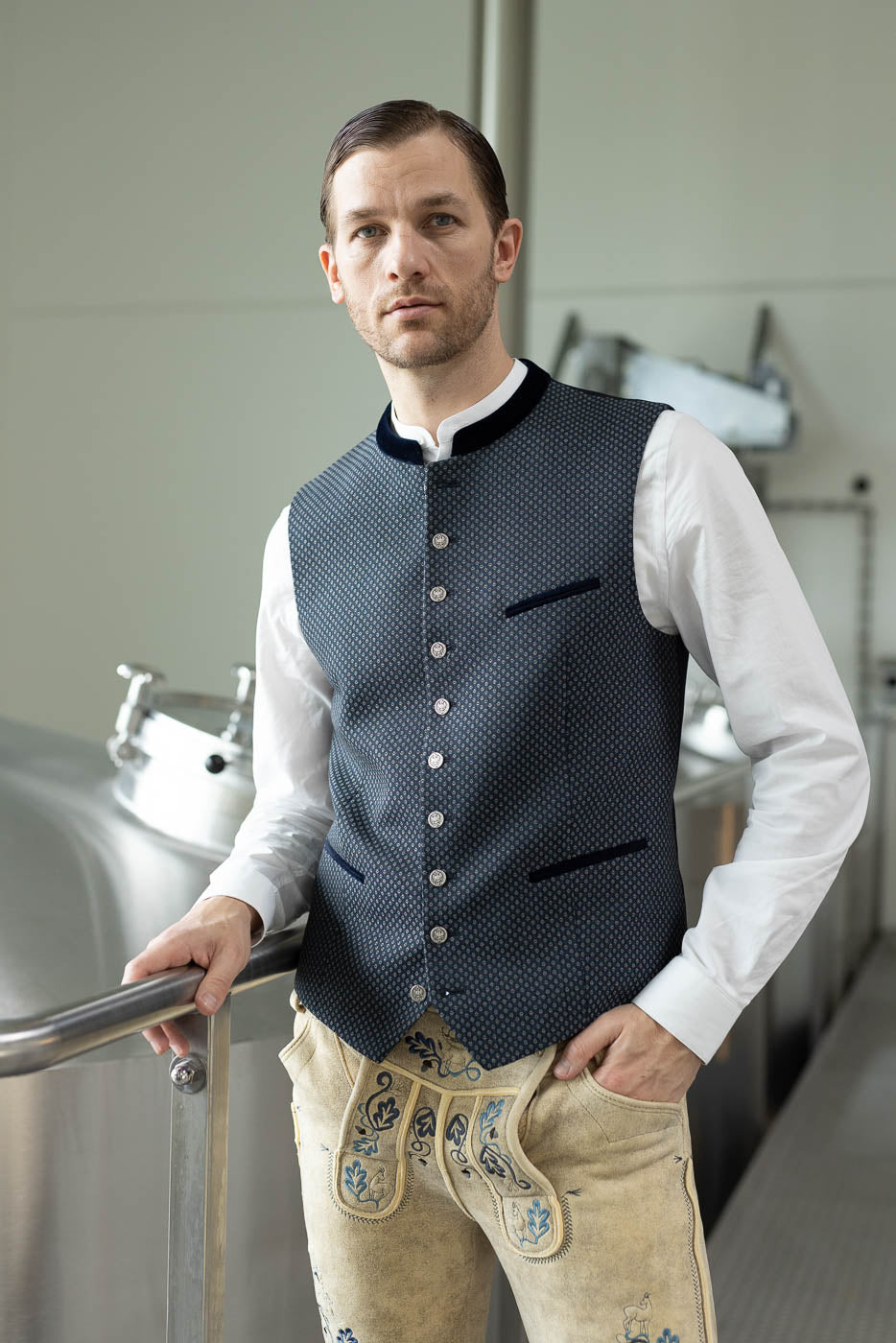 Gemusterte Trachtenweste in Blau mit weißem Trachtenhemd und heller Hirschlederhose.