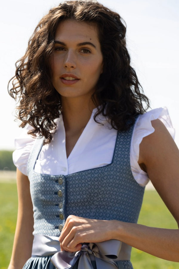 Model mit Dirndl in Blau und einer weissen Trachtenbluse mit Flügelarm.